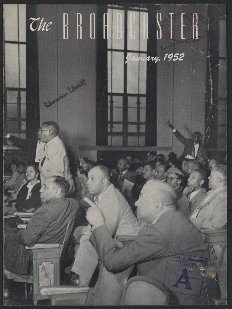 Black men sitting in a meeting, some pointing towards the front