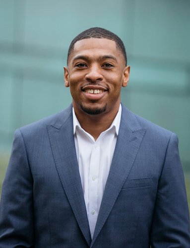 A portrait of a Black man in a blue suit.