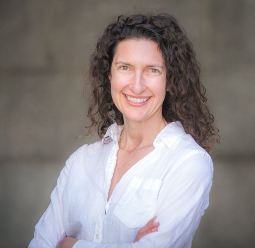 A portrait of a white woman with brown hair wearing a white shirt.