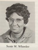 A portrait of a Black woman with short curly hair and cat-eye glasses.